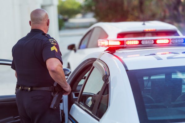 police officer stands next to his car before approaching accident