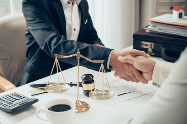 lawyers shake hands over a desk