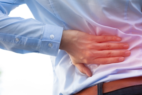 man holds sore spot on his back after a car accident