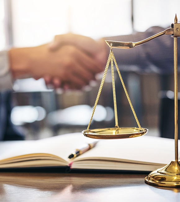 lawyers shaking hands next to scales of justice and gavel